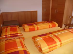 a room with two beds with orange and orange sheets at Apartments Ferdigg in San Lorenzo di Sebato