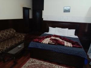 Ce lit se trouve dans un dortoir doté d'un canapé et d'un lit sidx sidx. dans l'établissement New Islamabad Guest House, à Islamabad
