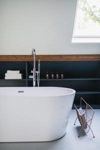 y baño con bañera blanca y lavamanos. en The Annex Retreat - a luxury countryside villa, en Geysteren