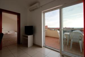 a room with a balcony with a table and a television at Apartments Bella in Novalja