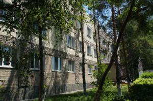 a brick building with trees in front of it at GALIRAD Hotel in Ustʼ-Kamenogorsk