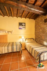 a bedroom with two beds and a stone wall at Albergue El Solitario in Baños de Montemayor