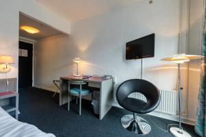 Habitación de hotel con escritorio y TV en la pared en HotelVFjorden, en Lemvig