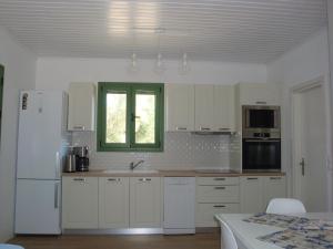 a kitchen with a white refrigerator and a window at Peter's Cottage, Near Fiscardo, Kefalonia in Fiskardho