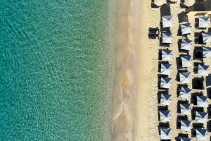 a row of beach chairs next to a body of water at Royal Myconian - Leading Hotels of the World in Elia Beach