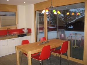 a kitchen with a wooden table and red chairs at Pradin 1 in Arosa