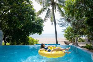 duas mulheres deitadas numa câmara de ar numa piscina ao lado da praia em Veranda Resort & Villas Hua Hin Cha Am em Cha Am