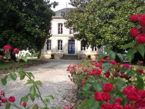 a white house with red roses in front of it at Château des Grandes Vignes in Preignac