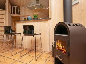 cocina con estufa de leña y 2 taburetes en 8 person holiday home in Fjerritslev en Torup Strand