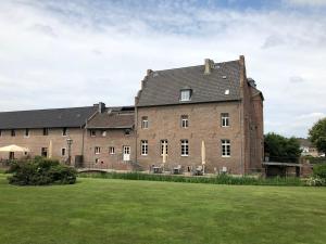 un gran edificio de ladrillo con un campo verde delante de él en Burg Obbendorf, en Niederzier