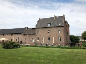 a large brick building with a green field in front of it at Burg Obbendorf in Niederzier