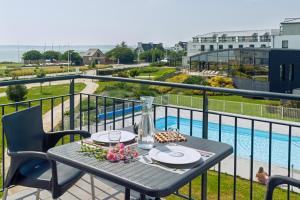 a table on a balcony with a view of a pool at Residence Thalasso Concarneau in Concarneau