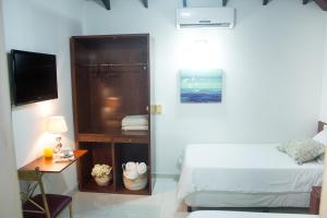Schlafzimmer mit einem Bett, einem Schreibtisch und einem TV in der Unterkunft Beulah Hotel Boutique in Asunción
