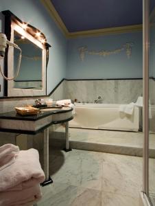 uma casa de banho com uma banheira, um lavatório e um espelho. em Hotel Villa Borghesi em Corte dei Cortesi