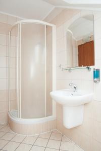 a white bathroom with a sink and a shower at Penzión Centrum in Oravský Biely Potok