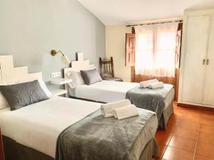 a hotel room with two beds and a window at Hotel Rural Tia Margot in Candelario