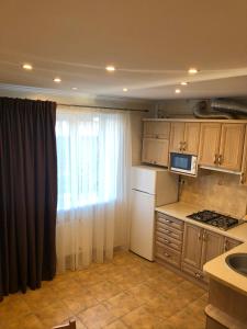 a kitchen with wooden cabinets and a window with a microwave at LvivBalabana in Lviv