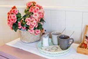 una olla de rosas rosas sentadas en un mostrador con dos tazas en Io&te spazio benessere, en Sordevolo