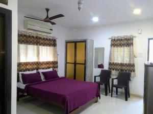 シオリムにあるDSK Studio Apartment, Siolim, Goa.のベッドルーム(紫色のベッド1台、テーブル、椅子付)