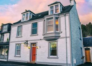 una casa blanca con una puerta roja en una calle en Queensberry House B&B, en Moffat