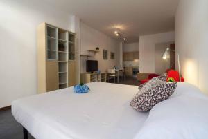 a bedroom with a white bed and a living room at Galleria Roma Apartment - Affitti Brevi Italia in Lecco