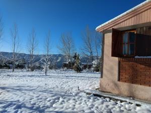 una casa en un patio cubierto de nieve con un edificio en Casa Montaña Valle del Sol en Potrerillos
