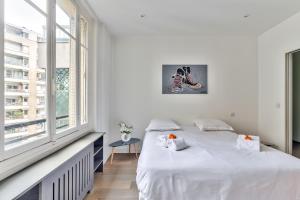 a white bedroom with a bed and a window at Modern & Bright Flat in Le Marais - An Ecoloflat in Paris