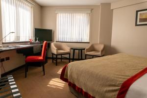 una camera d'albergo con letto, scrivania e sedie di Neuquén Tower Hotel a Neuquén