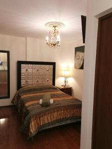 a bedroom with a large bed and a chandelier at Acogedor y Elegante Estudio cerca al Prado in Cochabamba