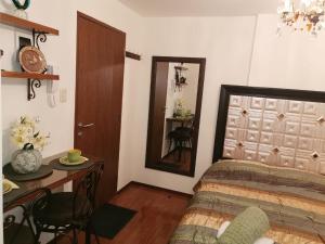 1 dormitorio con cama, mesa y espejo en Acogedor y Elegante Estudio cerca al Prado, en Cochabamba