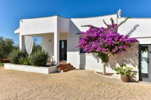 a white house with a tree with purple flowers at Torre San Martino in Polignano a Mare