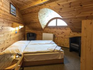 sypialnia z łóżkiem z 2 krzesłami i oknem w obiekcie EA Horský Hotel Hájenka w mieście Modrava