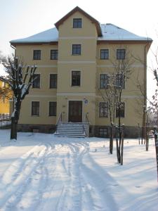 ein großes gelbes Gebäude mit Schnee davor in der Unterkunft Willa Pod Gwiazdami & SPA in Kudowa-Zdrój