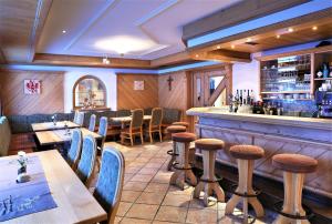 ein Restaurant mit Tischen und Stühlen und eine Bar in der Unterkunft Hotel Sabine in Galtür