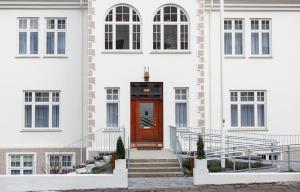 ein weißes Gebäude mit einer braunen Tür und einer Treppe in der Unterkunft Reykjavik Residence Apartment Hotel in Reykjavík