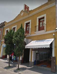 ein gelbes Gebäude mit weißer Markise auf einer Straße in der Unterkunft Hotel Centro Historico in Puebla