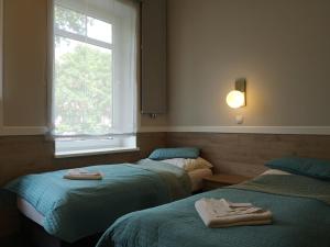 two beds in a room with a window and towels at Ośrodek Wczasowy Temida in Świnoujście