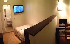 a hotel room with a bed and a television on the wall at Hotel Quinchamali in Chillán