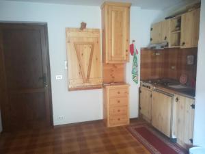 a kitchen with wooden cabinets and a door at monolocale Sabrina in Torgnon