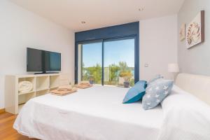a bedroom with a large white bed with a large window at Llevant in Portocolom
