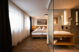 bagno con letto, lavandino e specchio di Hotel Brugger a Fulpmes