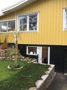 una casa amarilla con un pequeño árbol delante en Lägenhet centralt i Värnamo vid Apladalen, en Värnamo