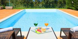 阿特里的住宿－Antica Melegnano，一张桌子,旁边放着两杯饮料和一盘水果,旁边是游泳池