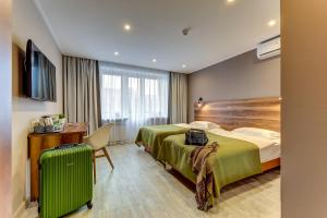 a hotel room with a bed and a suitcase at Orbita Hotel in Saint Petersburg