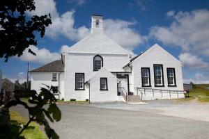 a white church with a tower on top of it at Ardnave in Port Charlotte