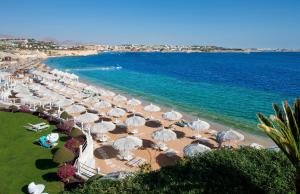 a beach with umbrellas and chairs and the ocean at Sunrise Arabian Beach Resort in Sharm El Sheikh