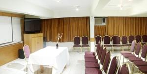 a conference room with a white table and purple chairs at Hotel Quinchamali in Chillán