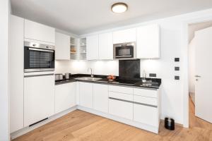 a white kitchen with white cabinets and black counter tops at lake and mountains appartements in Maishofen