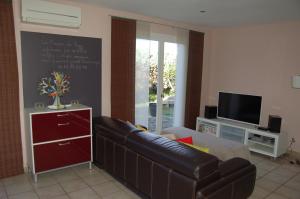 een woonkamer met een leren bank en een tv bij La Maison de Peggy in Garons
