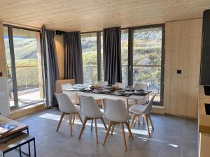 a dining room with a table and chairs and windows at Lagrange Vacances L’Écrin du Badet in Aragnouet
